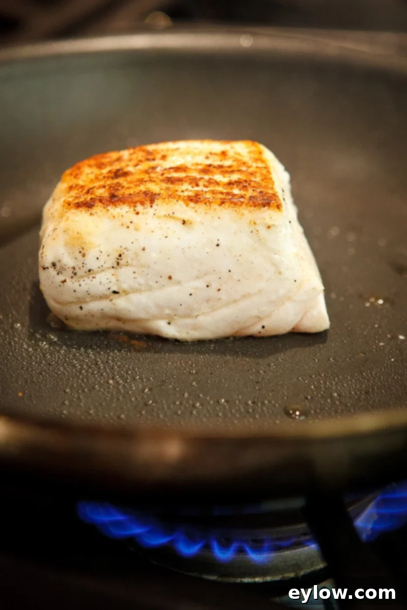 Crispy-skinned halibut fillet in a pan, ready to be served.