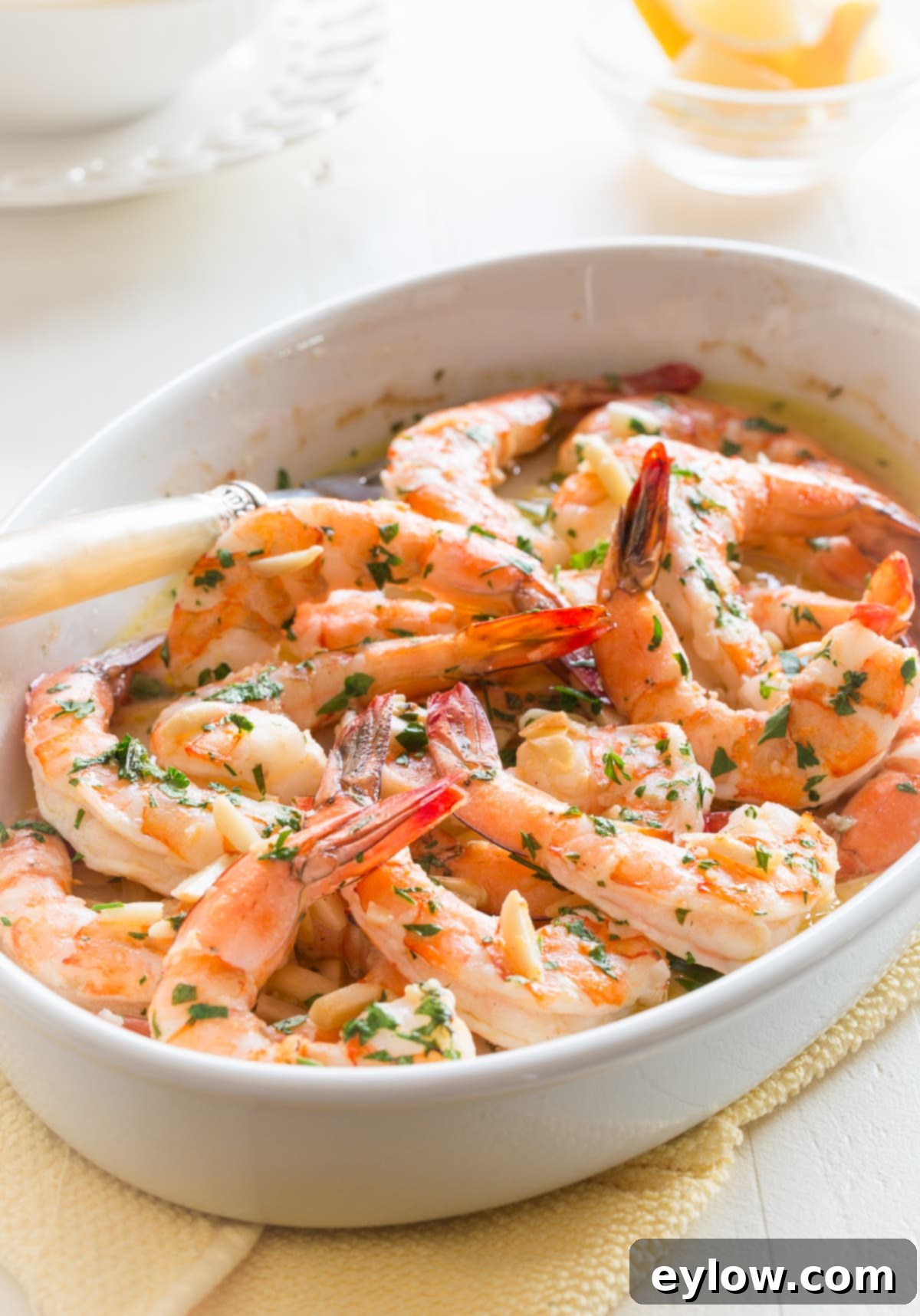 Effortless Oven-Baked Shrimp Scampi 2 Baked shrimp scampi in a white casserole dish with fresh parsley and lemon wedges, ready to serve.