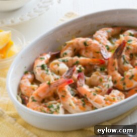 Effortless Oven-Baked Shrimp Scampi 7 baked lemon shrimp scampi in a white dish with lemon and parsley garnish