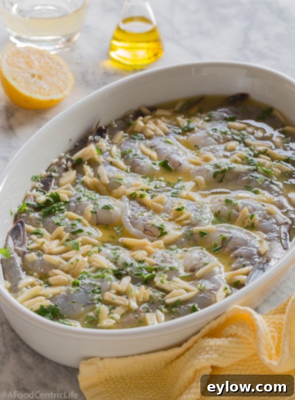 Effortless Oven-Baked Shrimp Scampi 5 Raw shrimp marinating in a white casserole dish with almonds and herbs, prior to baking.
