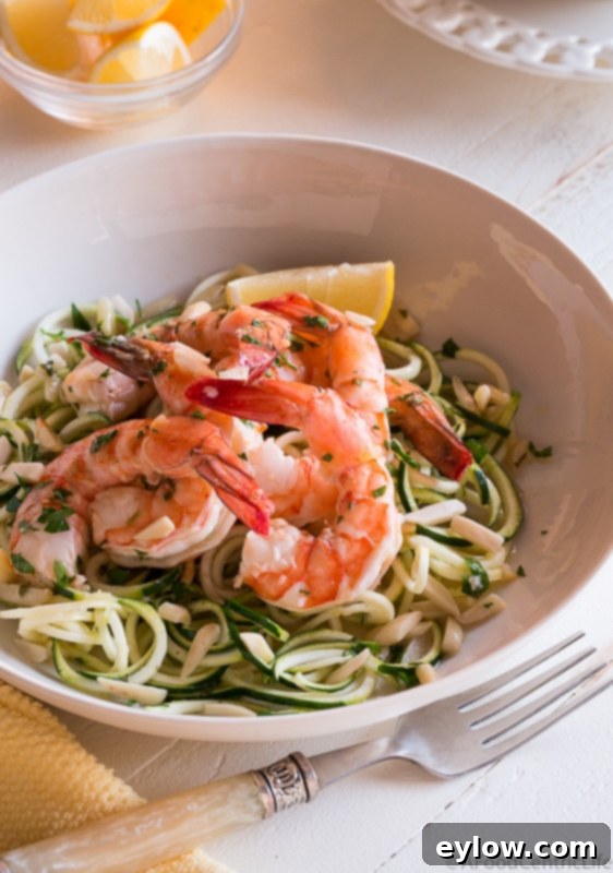 Effortless Oven-Baked Shrimp Scampi 6 Lemony shrimp scampi served over zucchini noodles in a white bowl with fresh herbs.