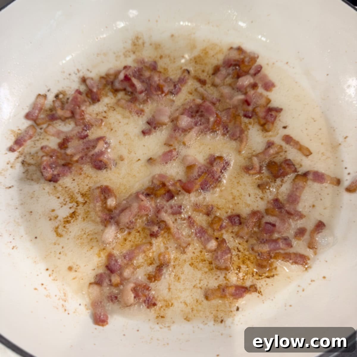 Frying chopped bacon in a shallow pan.