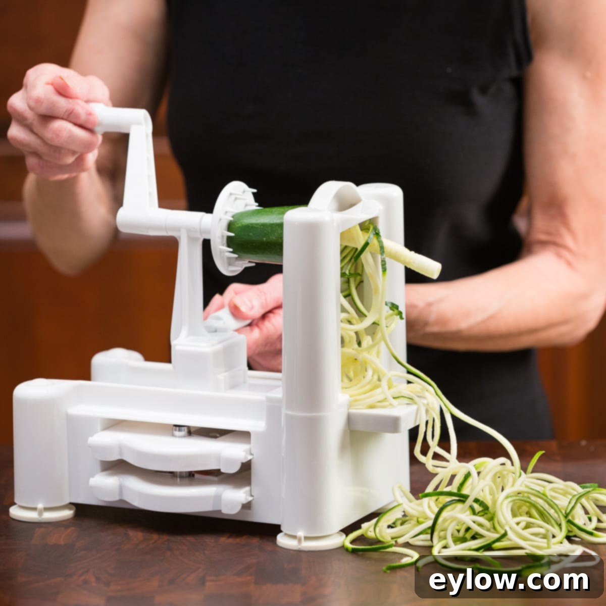 Zucchini noodles being made with a spiralizer tool.