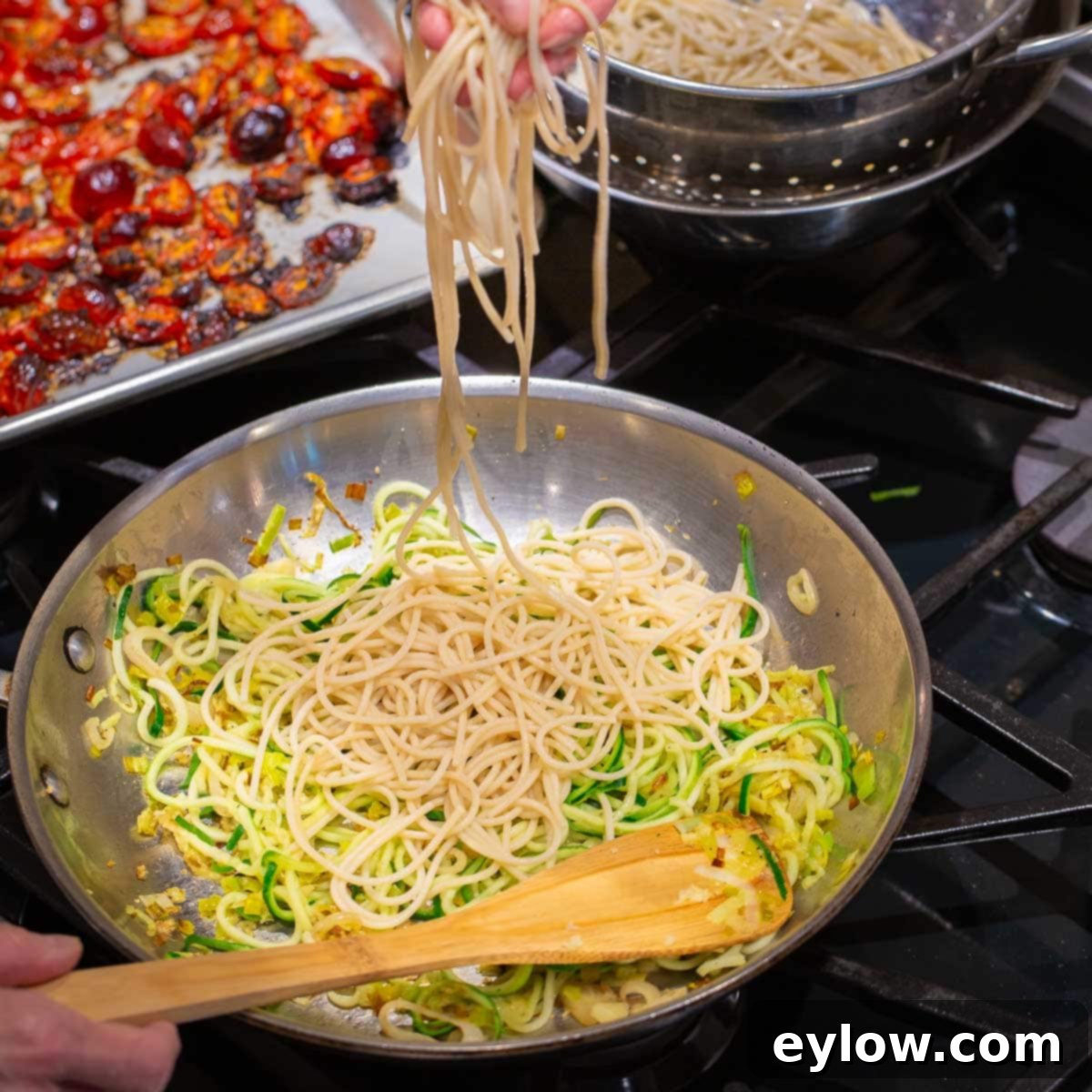 A pan of zucchini noodles and pasta with roasted red tomatoes. 