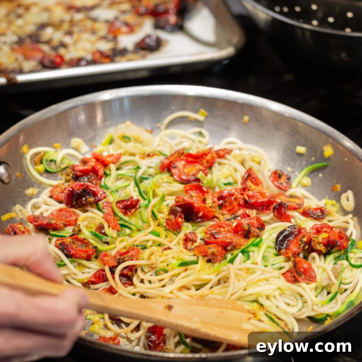 A pan of zucchini noddles and past noodles with roasted tomatoes.