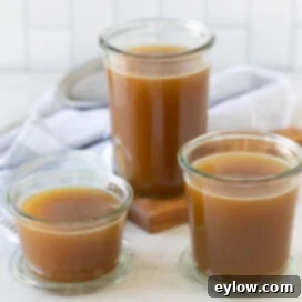 Homemade Turkey Stock 9 Rich brown roasted turkey broth in glass jars on a kitchen counter.