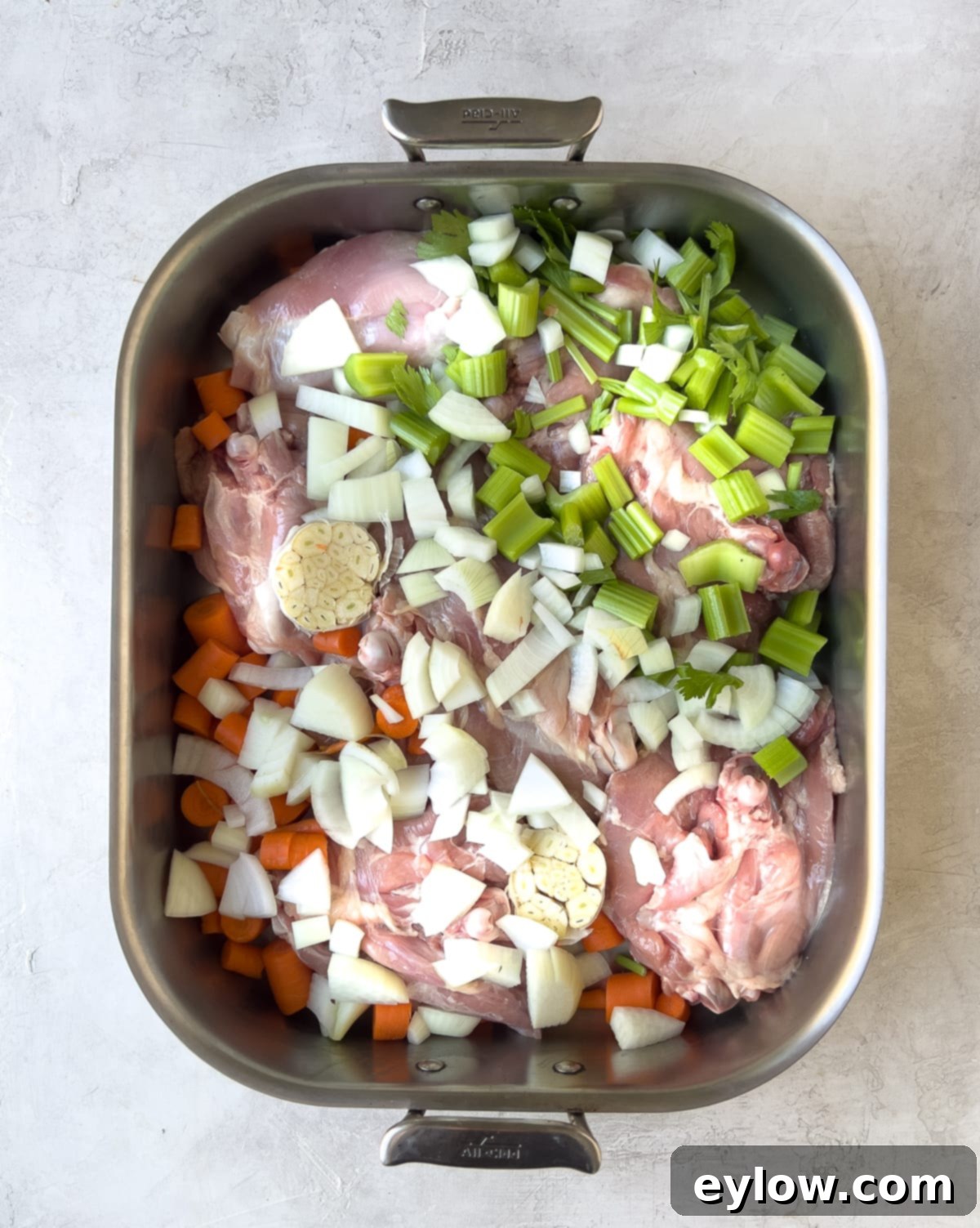 Homemade Turkey Stock 4 Raw turkey pieces and chopped vegetables in a roasting pan.