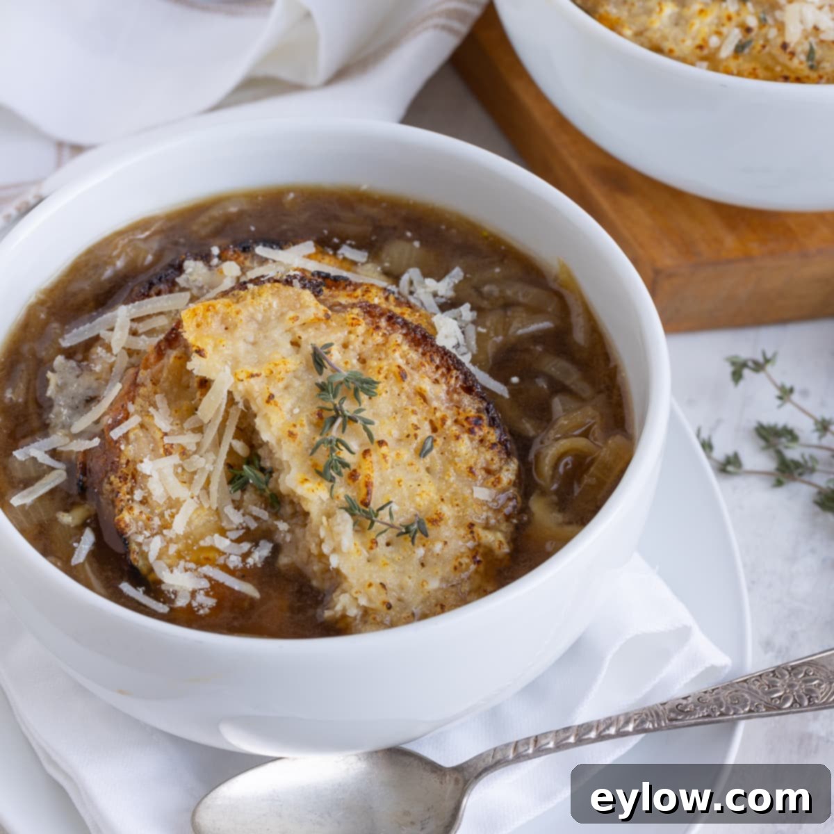 Homemade Turkey Stock 7 A white bowl of rich French onion soup with a cheesy crouton on top and sprinkle of fresh herbs.