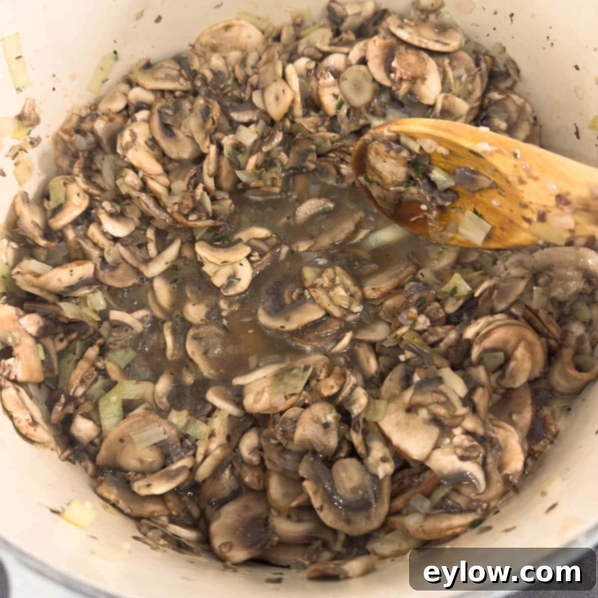 A heavy pot full of juicy cooking mushrooms as they give off their liquid, concentrating flavor.
