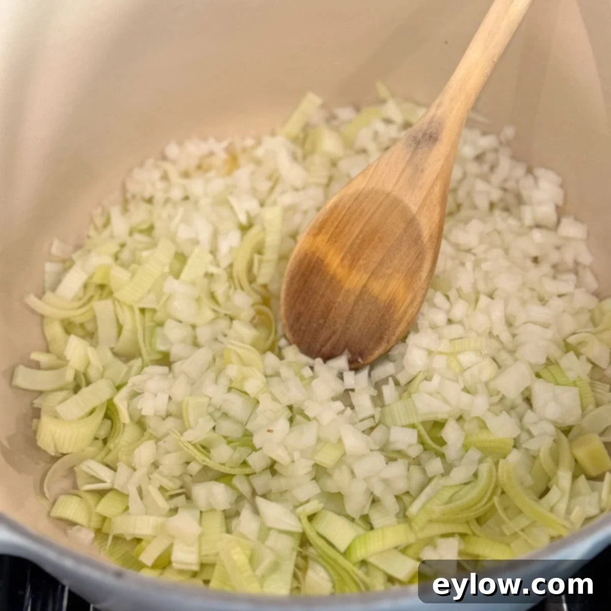 Chopped onions and leeks gently sautéing in a dutch oven to form a soup base.