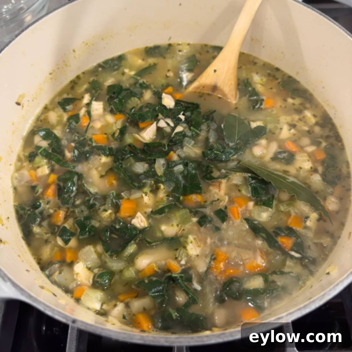 Adding kale to a soup pot for added vegetables and nutritoin.