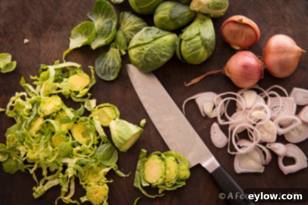 Thinly sliced Brussels sprouts meticulously arranged on a cutting board, accompanied by perfectly sliced shallots and a sharp chef's knife, showcasing all the fresh ingredients meticulously prepped and ready for the cooking process.