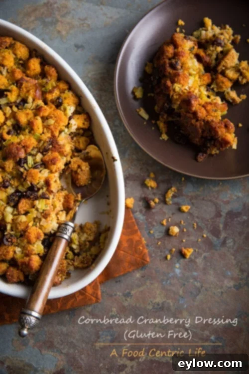 A festive gluten-free cornbread cranberry dressing in a casserole dish, garnished with fresh herbs.