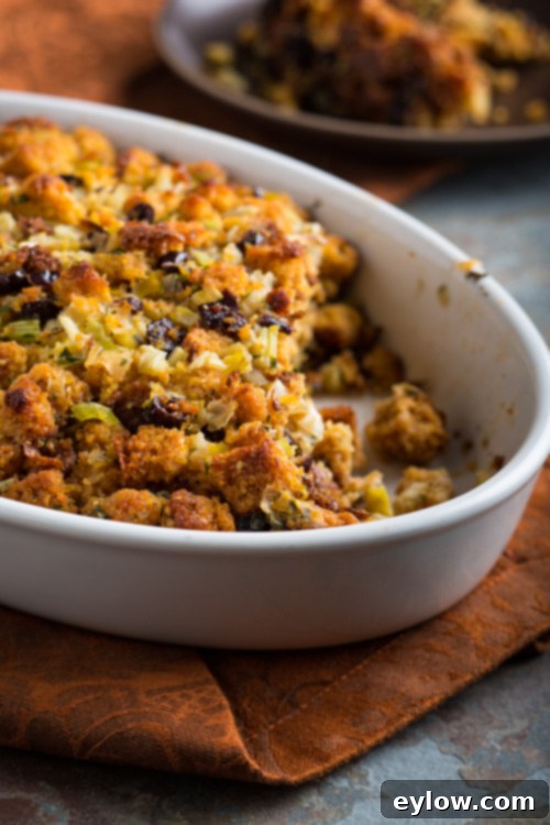 A close-up view of the golden-brown gluten-free cornbread cranberry dressing, showing the herbs and cranberries on top.
