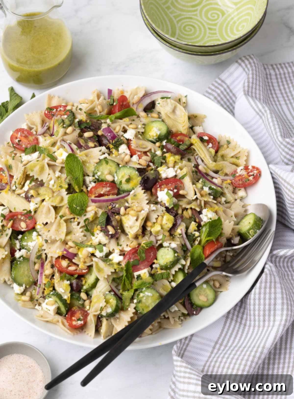 Colorful Mediterranean pasta salad in a large white serving bowl. 
