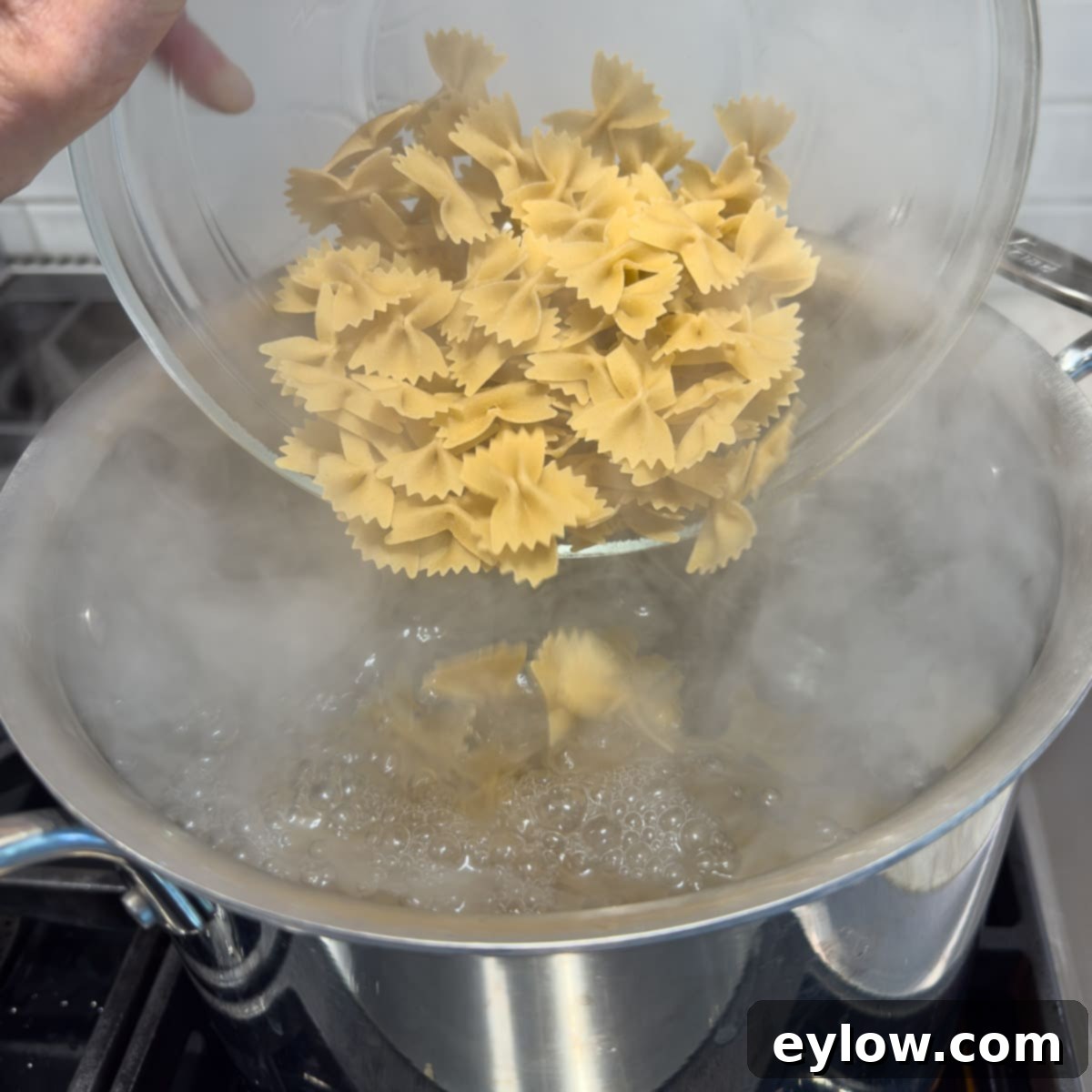 Pouring dry pasta into a large pot of boiling water to cook.