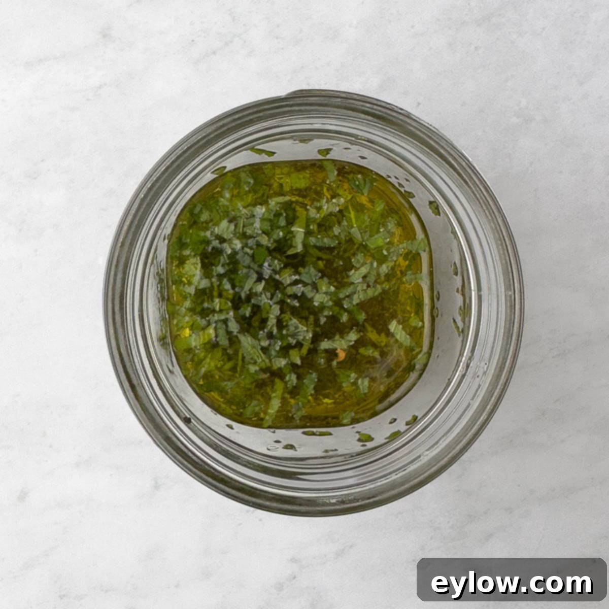 Dressing ingredients of fresh herbs and olive oil in a jar. 