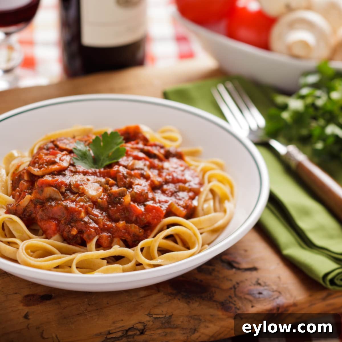 Rich and hearty pasta sauce with mushrooms over fettuccine noodles in a white bowl.