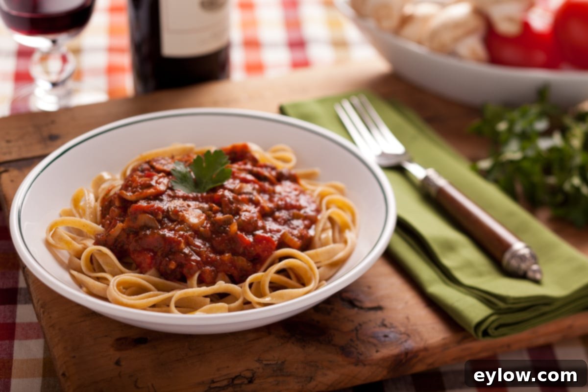Pasta in a white bowl topped with mushroom marinara on a dinner table.