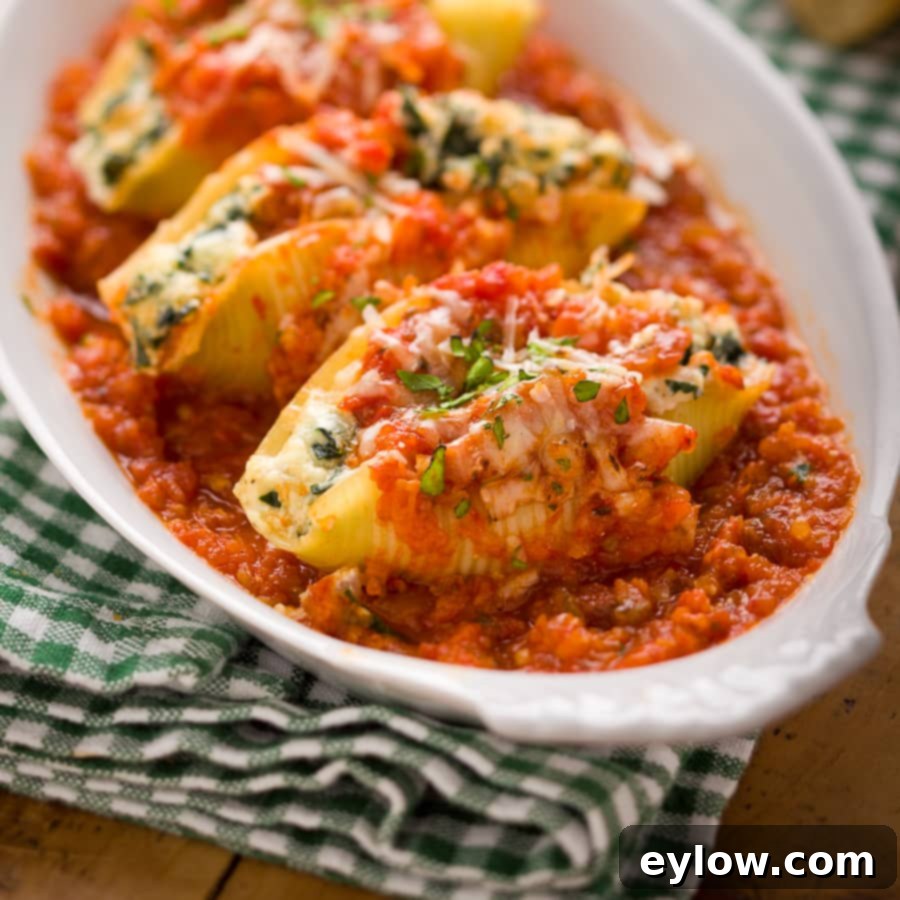 An oval baking dish of pasta stuffed with ricotta, kale and topped with cheese and marinara. 