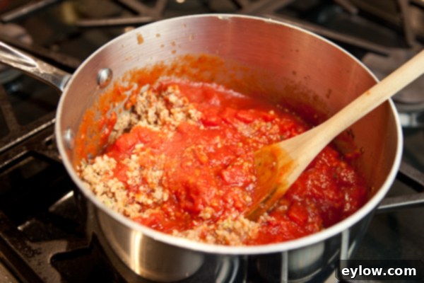 Sauce for lasagna simmering in a large pot, showing the rich red color and texture.
