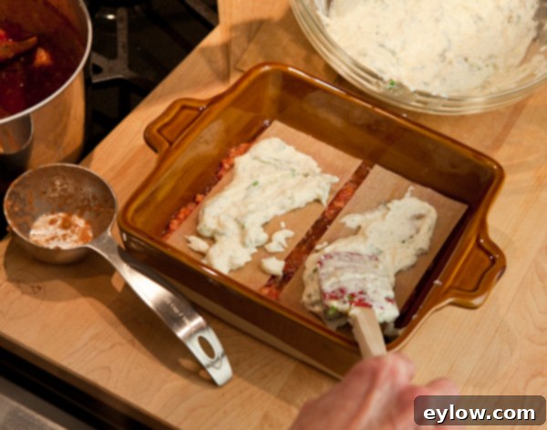 How to layer lasagna step 1, showing the initial sauce and noodle layer.