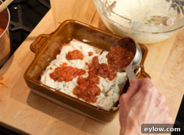 How to layer lasagna step 2, showing the ricotta and mozzarella layers.