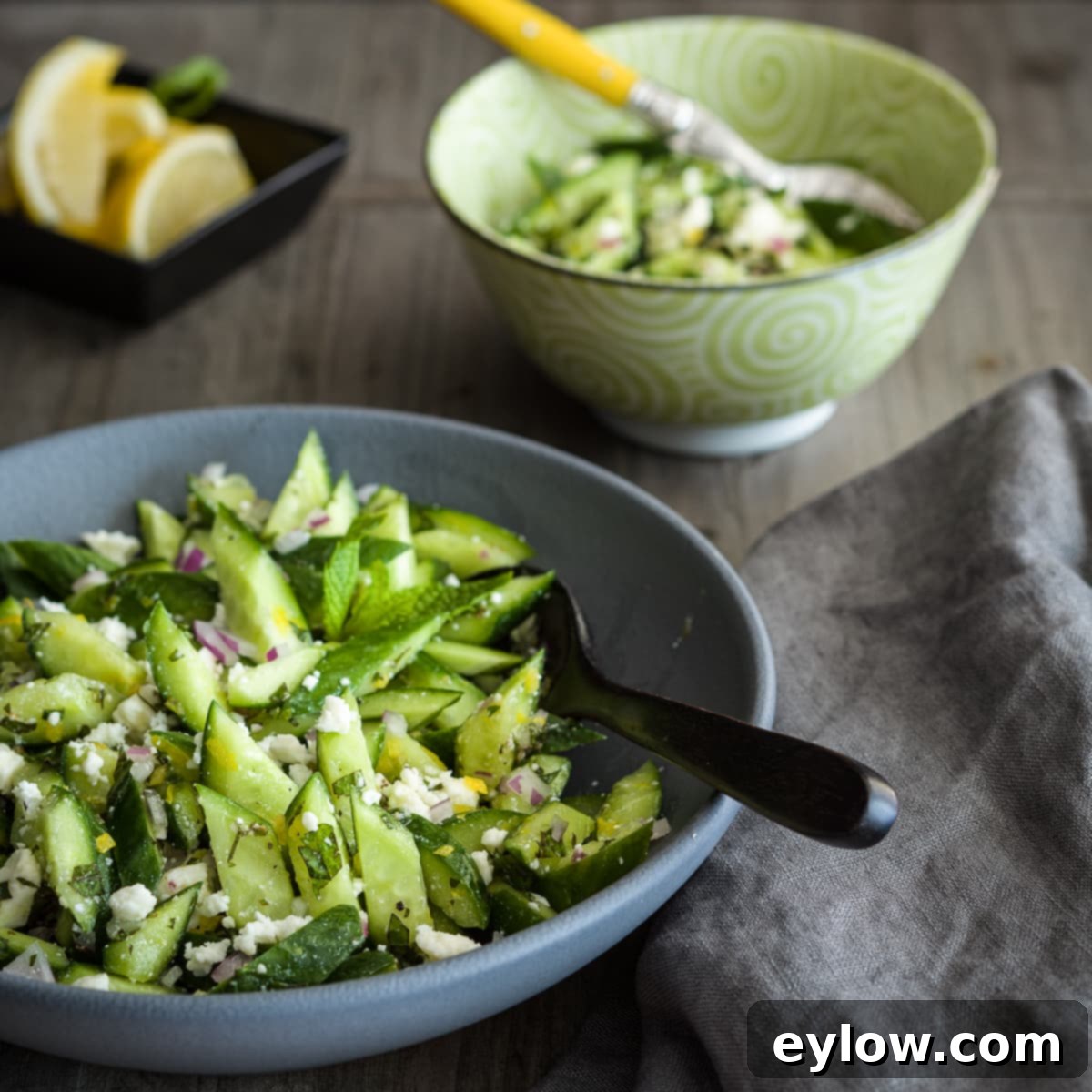 Crisp Cucumber Dill Feta Medley 2 A salad of chopped green cucumbers, dill, feta, and red onions in a bowl with serving spoon.