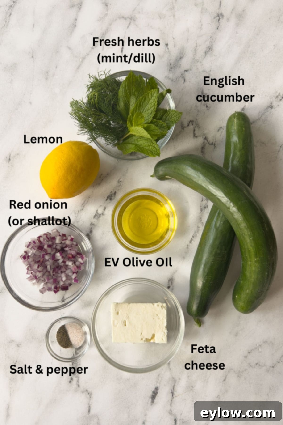 Crisp Cucumber Dill Feta Medley 3 Ingredients for cucumber salad on the counter with feta, onion, herbs, and lemon.