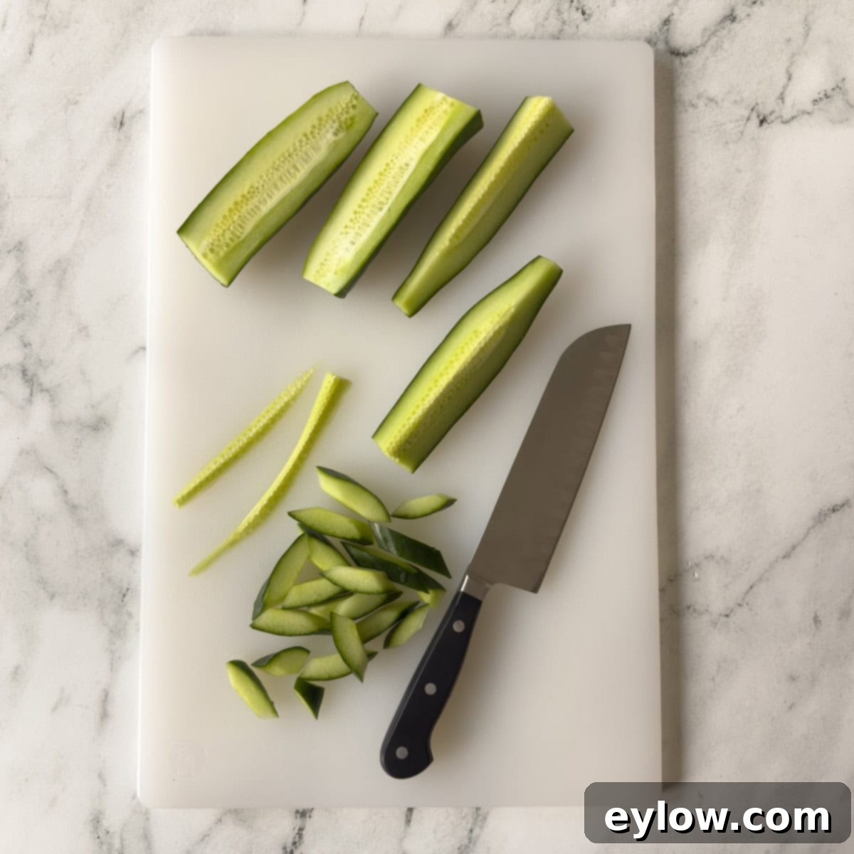 Crisp Cucumber Dill Feta Medley 4 Chopping cucumbers for salad on a white cutting board with a knife.