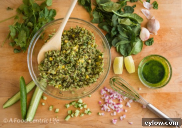 Ingredients for Avocado Quinoa Salad being prepared in a glass bowl on a cutting board, with spinach and lime visible.