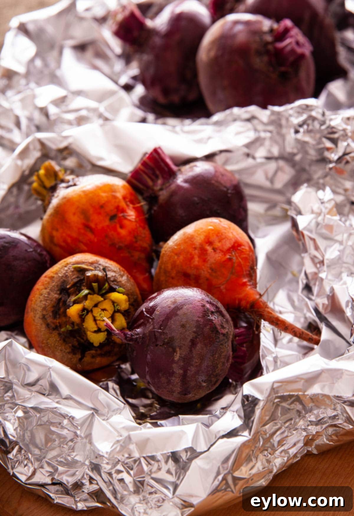 Red and gold beets roasting in aluminum foil with oil. 