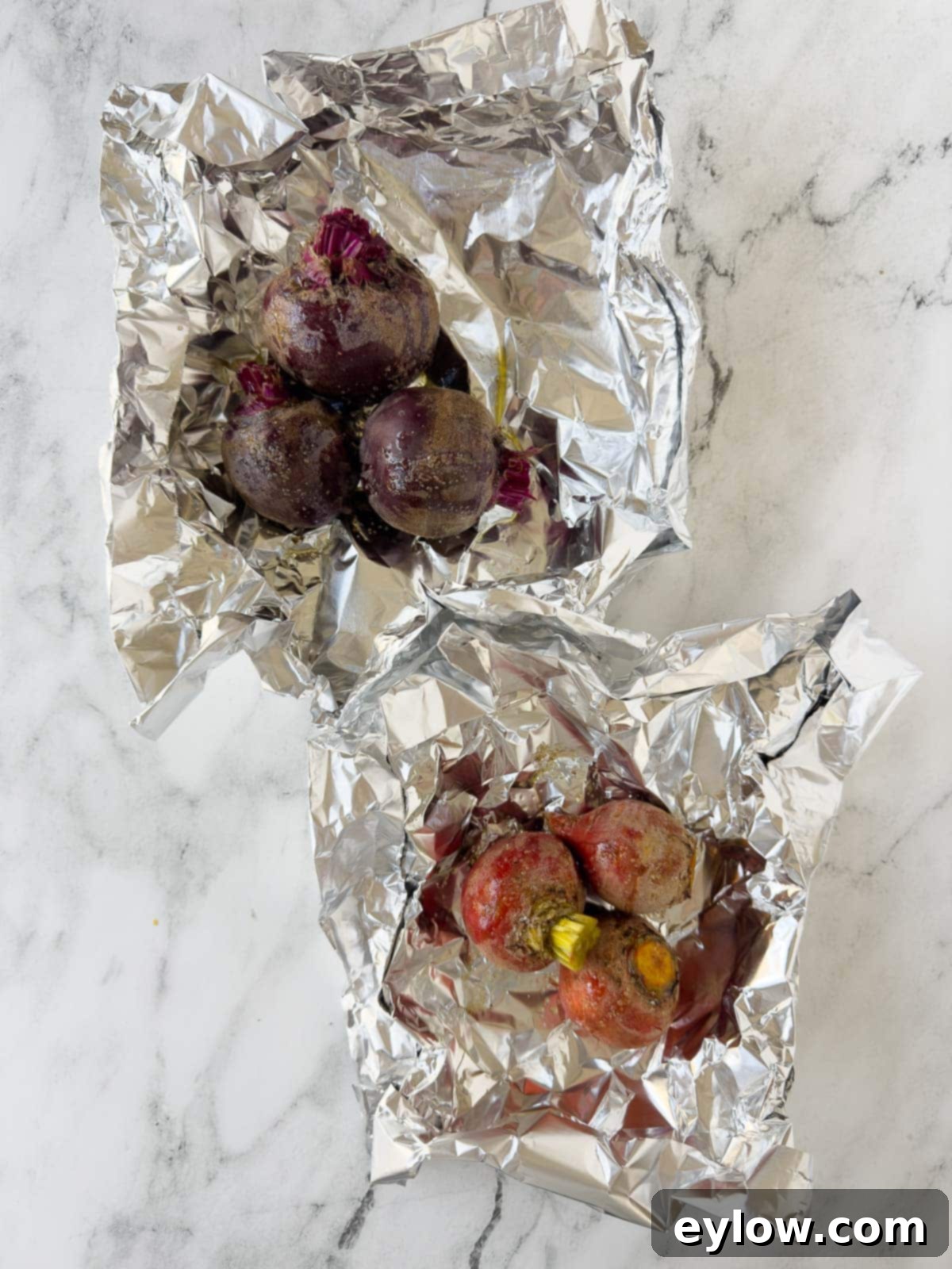 Red and gold beet in aluminum foil packets drizzled with oil and salt.