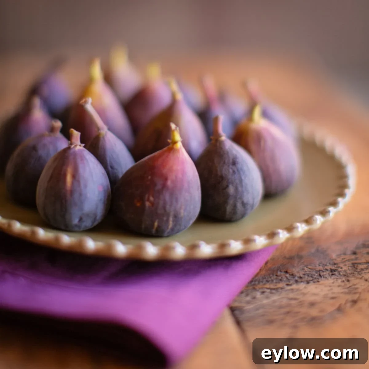 Beautiful ripe purple figs artfully arranged on a rustic wooden plate, ready for culinary use or simple enjoyment.
