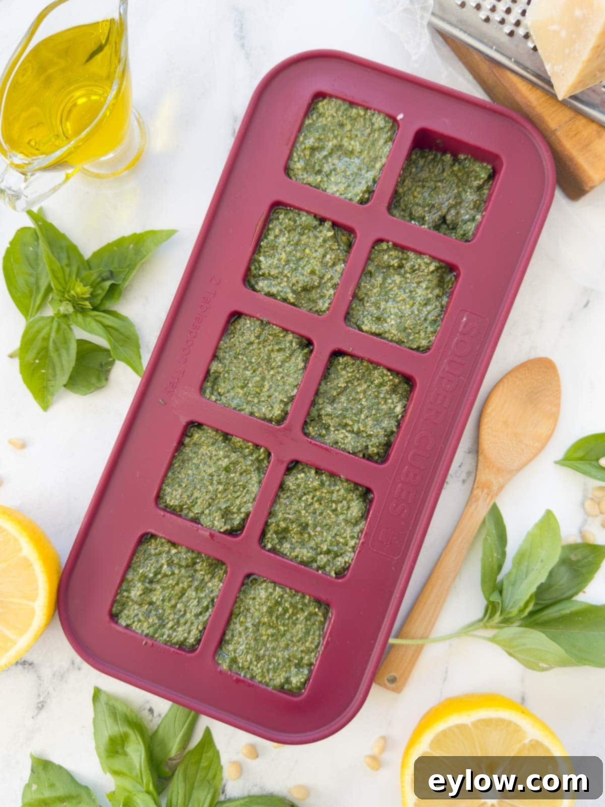 Genovese Basil Pesto: The Original Italian Recipe 6 Bright green basil pesto perfectly portioned in a cranberry Souper Cubes tray, ready for freezing, showcasing an ideal method for long-term storage.