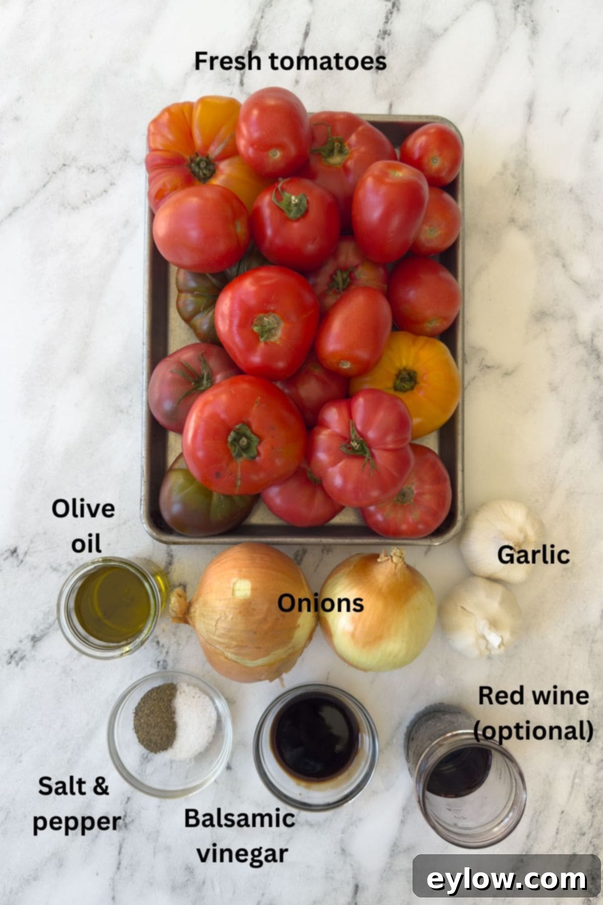 Ingredients for roasted tomato sauce on a marble counter with tomatoes, onion, garlic, oil, wine.