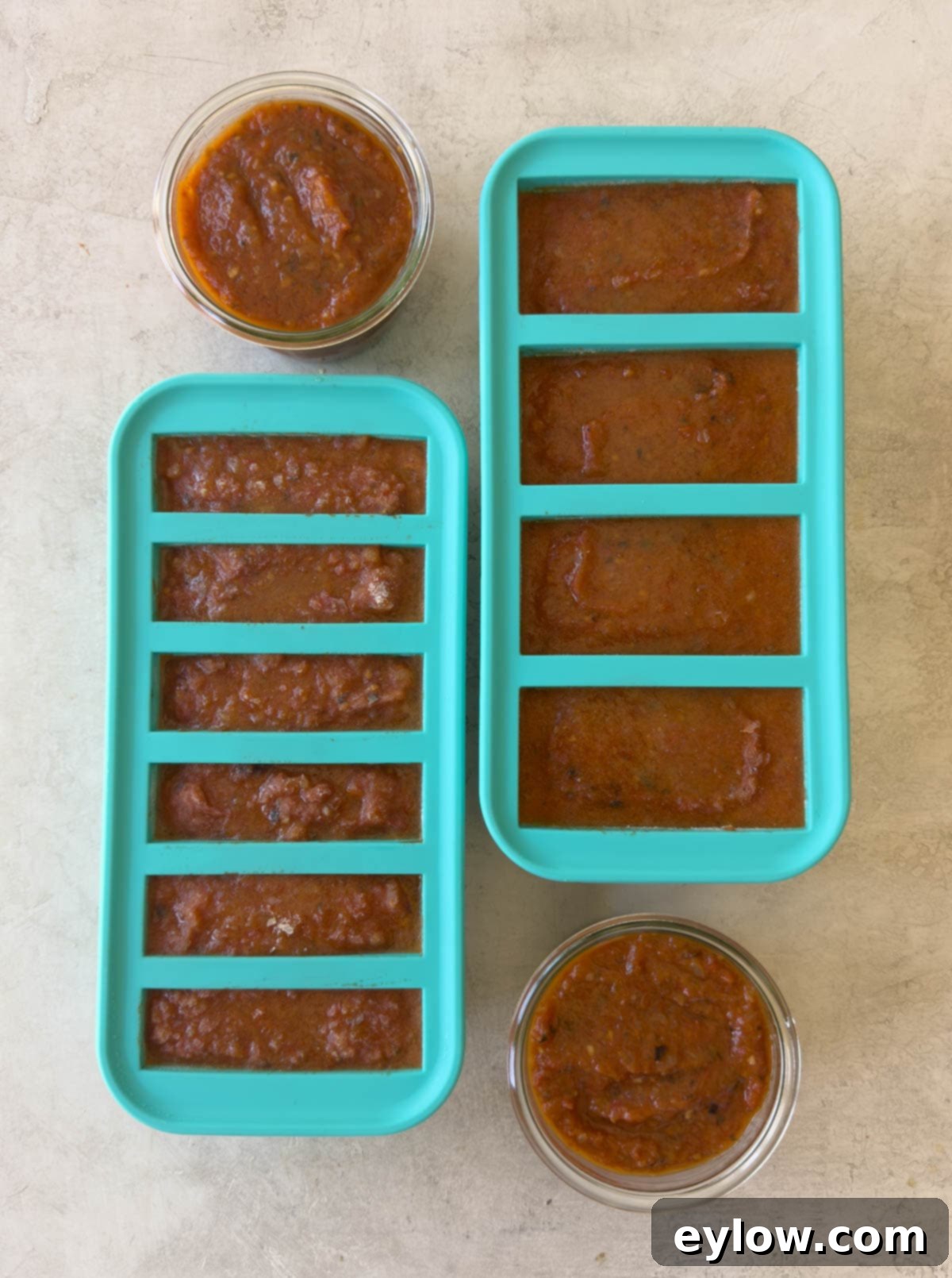 Finished tomato sauce in glass jars and silicone molds for freezing.