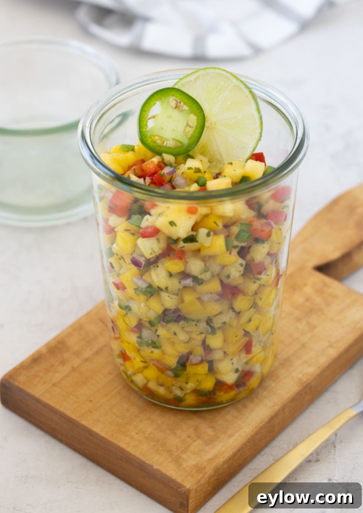 A glass jar filled to the brim with colorful, freshly made pineapple mango salsa, ready to be enjoyed.