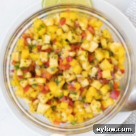 A glass bowl of bright tropical colored pineapple mango salsa, perfect for serving.
