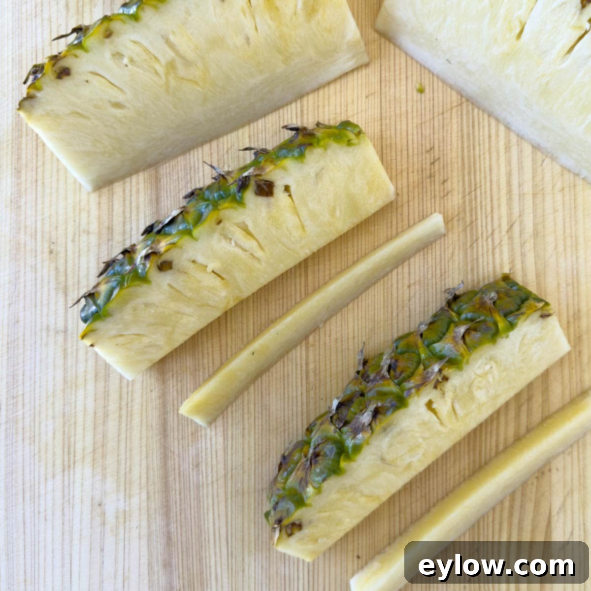 A pineapple spear on a cutting board, with a knife expertly removing the fibrous inner core.