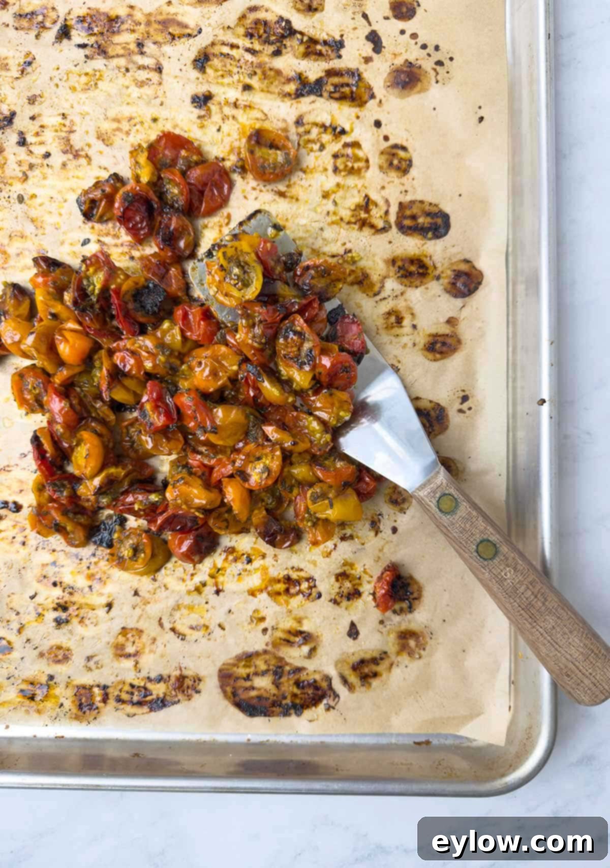 Herb Roasted Cherry tomatoes | AFoodCentricLife.com Cherry tomatoes after roasting on baking tray, browned and jammy. The tomatoes are glistening with reduced juices and herbs.