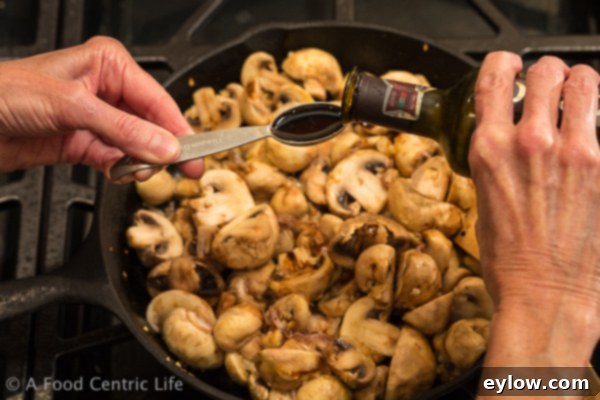 Sautéed mushrooms browning in a cast iron skillet with shallots and garlic, releasing their moisture and caramelizing.