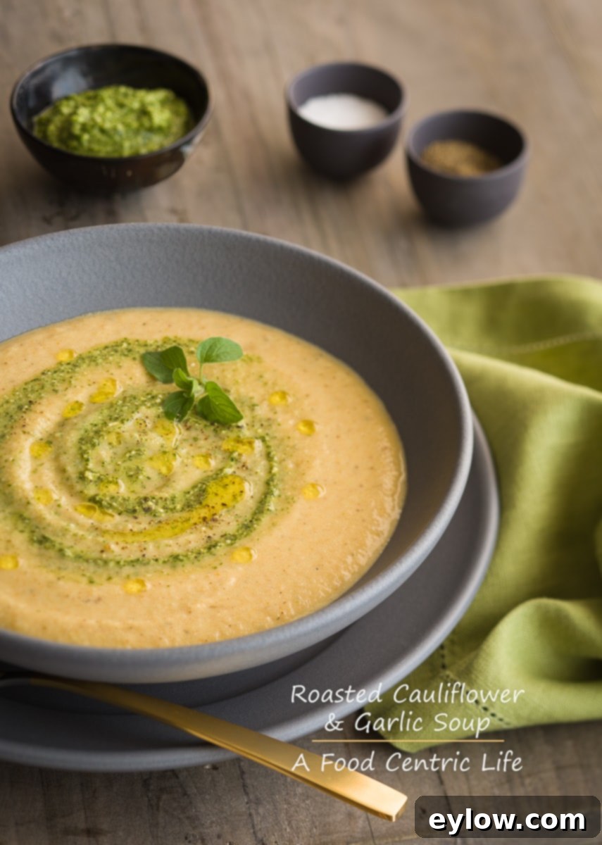 Roasted cauliflower soup in gray bowl with pesto swirl garnish.
