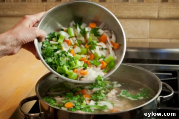 Adding the vegetables to the pot. 