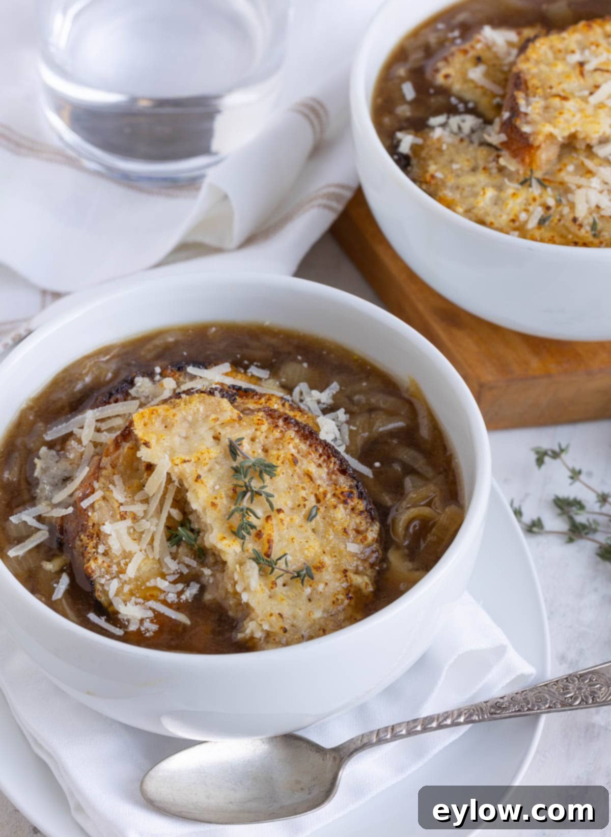 Effortless French Onion Soup 2 Bowls of rich brown French onion soup topped with cheesy golden croutons and fresh thyme garnish.
