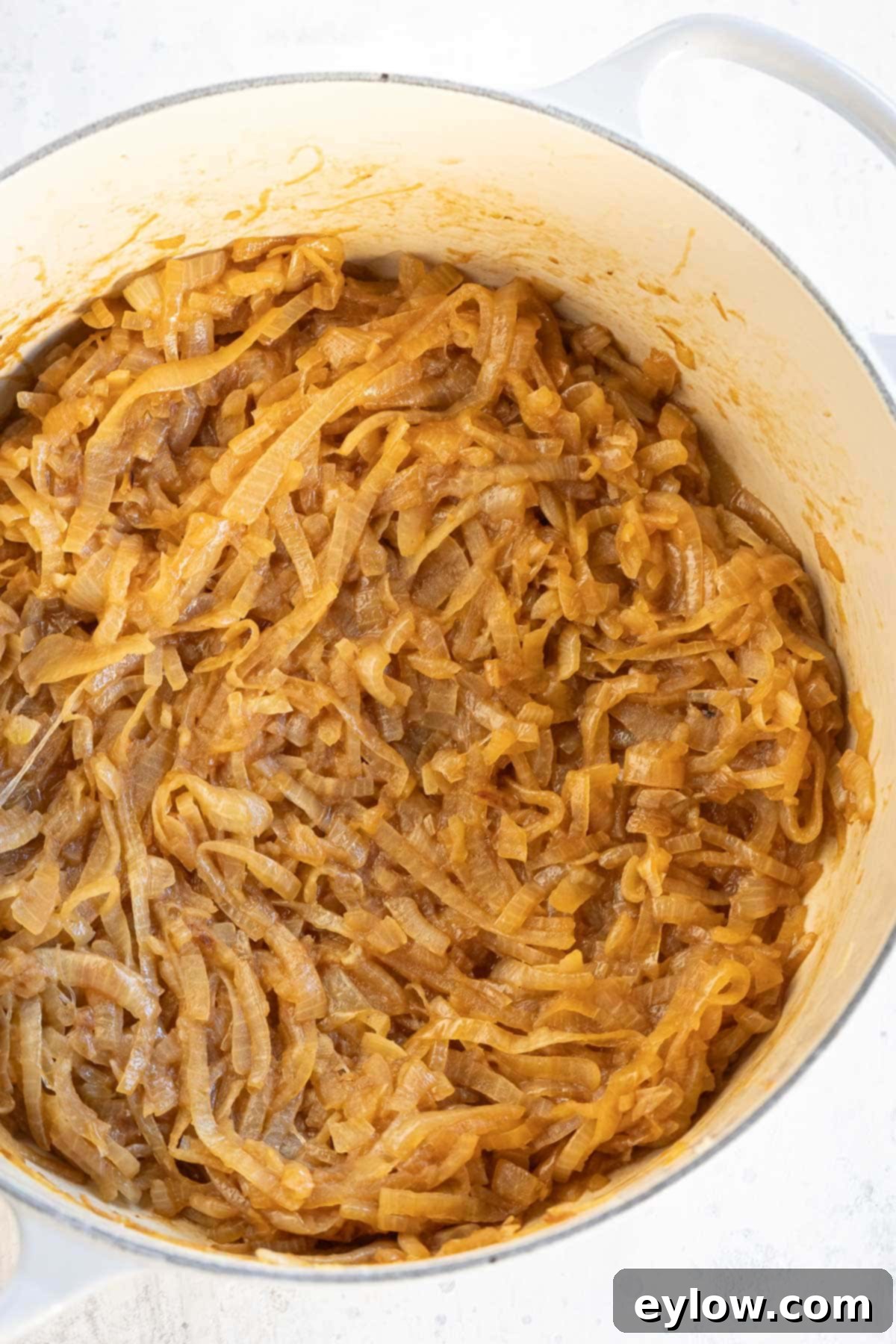 Effortless French Onion Soup 4 A large pot full of richly browned caramelized onions for onion soup, showcasing their deep amber color.