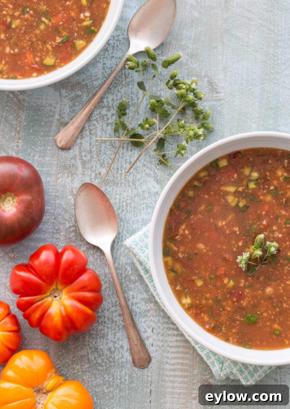 Andalusian Gazpacho Chilled Spanish Tomato Soup 2 Bowl of gazpacho andaluz soup with silver spoons and heirloom tomatoes on the side.