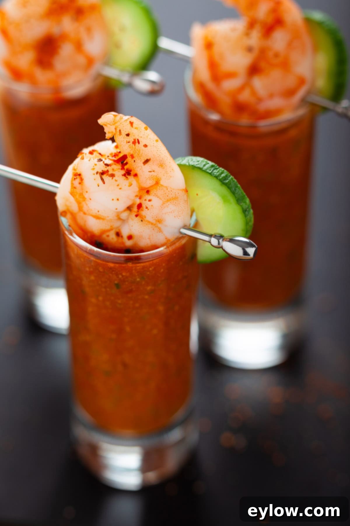 Gazpacho Shooters-4788 Glass shooters filled with gazpacho, topped with a shrimp and cucumber garnish with a silver pick.