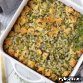 Classic golden-brown stuffing in a white casserole dish, garnished with fresh herbs.