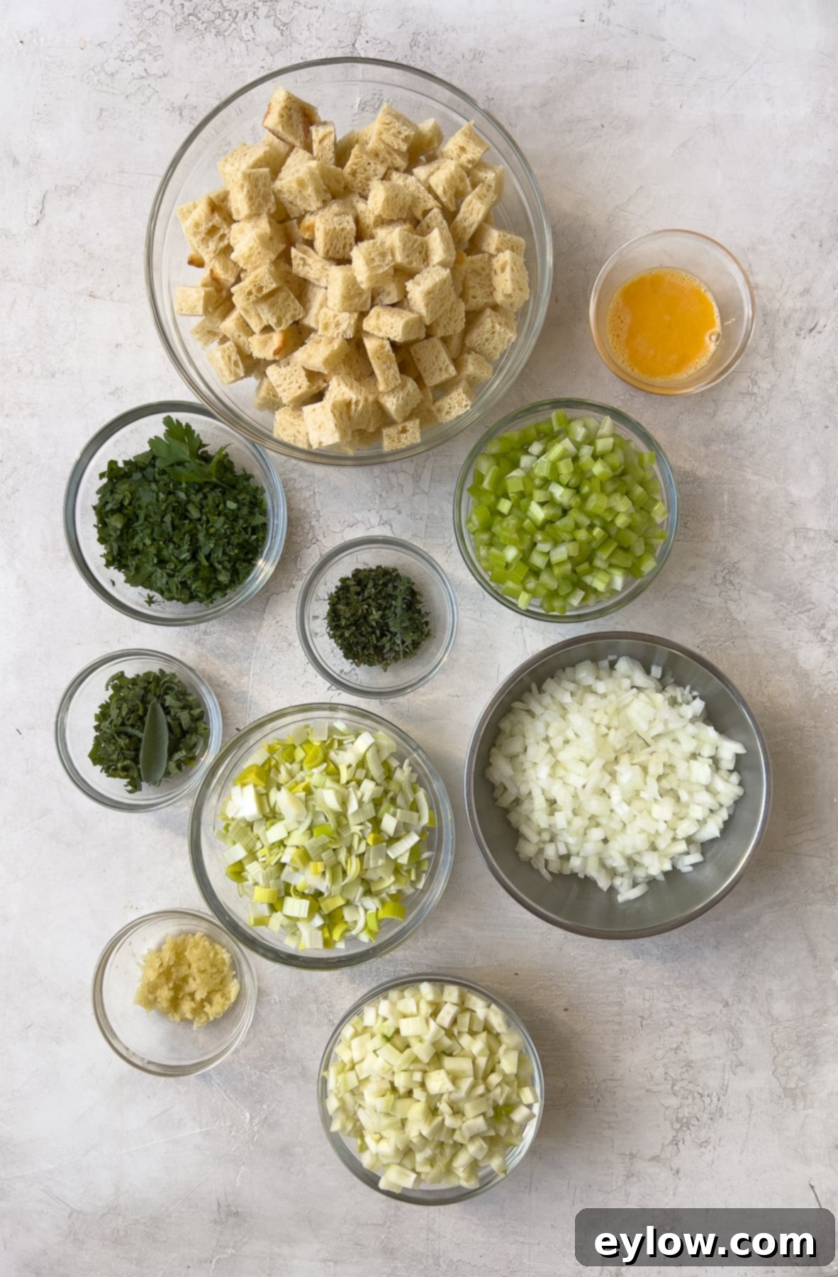 Prepped stuffing ingredients in separate bowls, including chopped vegetables and bread cubes, ready for cooking.